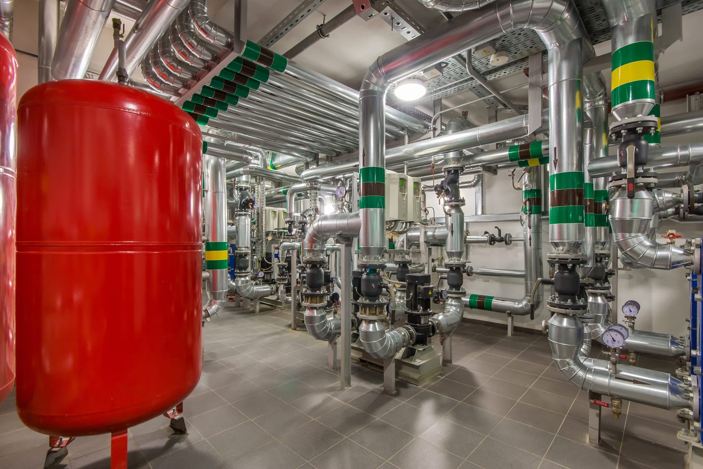 Plant room with pumps, pipework and a red expansion vessel